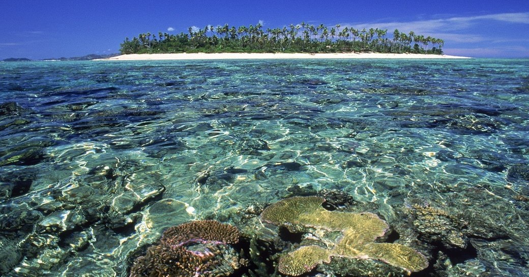 clear waters and coral of Fiji with uninhabited island in the background