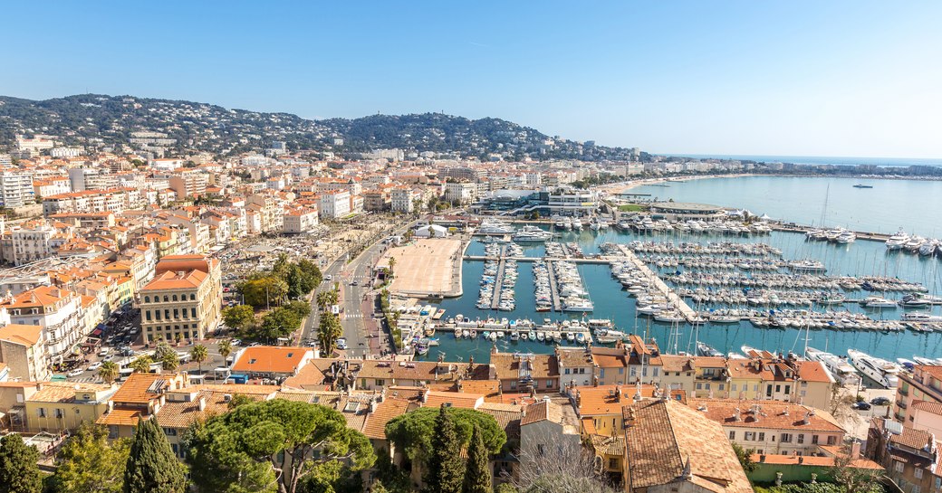 Elevated view of Cannes Vieux Port over rooftops. View of the Bay of Cannes in distance.