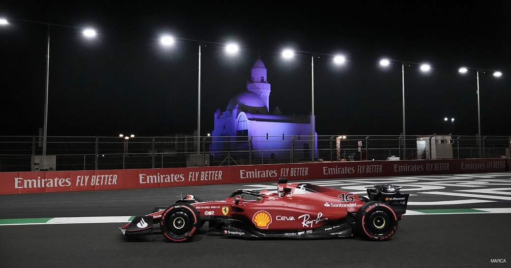 Side view of a Formula ONe car on the Saudi Arabia track at night, with the Mosque lit by subtle lights in background.