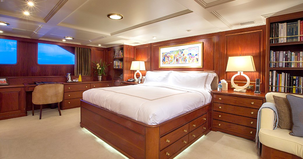 the capacious and sophisticated master suit with desk and vanity illuminated by deicreet lighting inside charter yacht Lady J