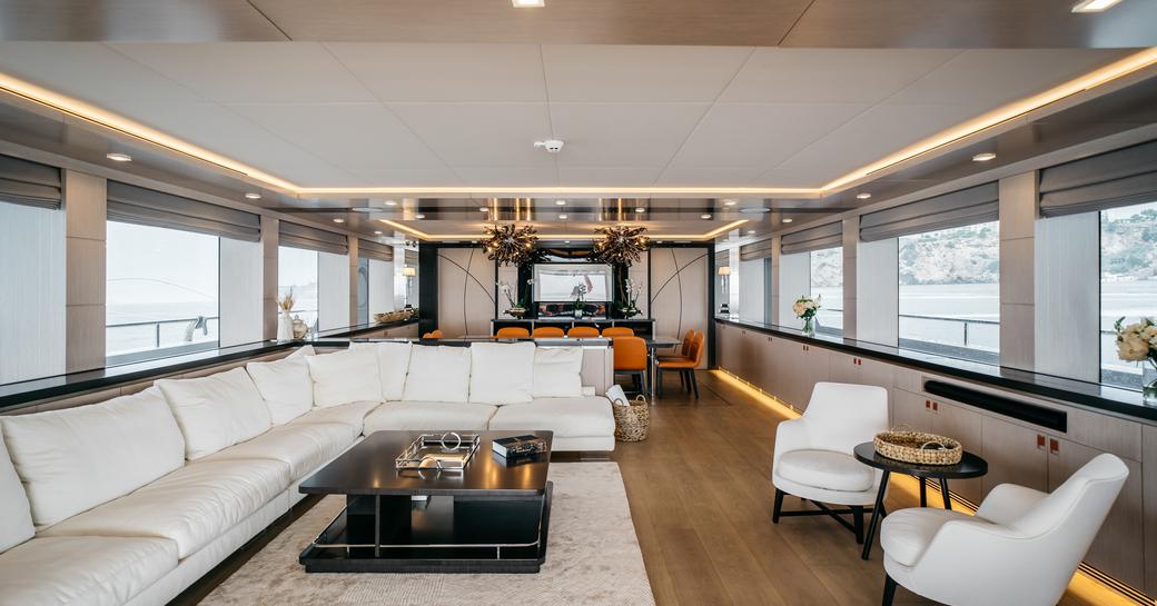 Overview of the main salon onboard charter yacht HEEUS with large whit sofa and pair of armchairs