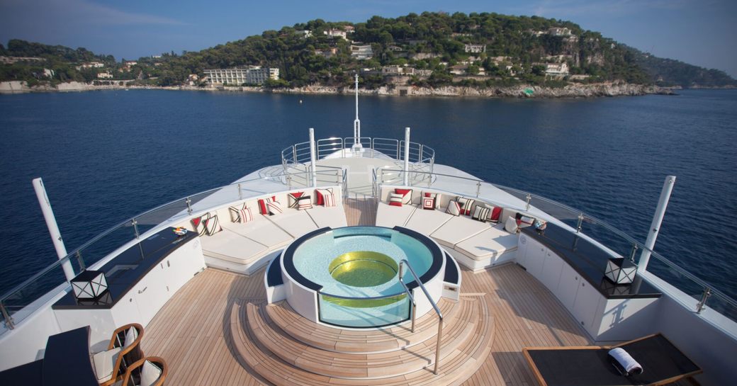 Elevated view looking down on deck Jacuzzi and sun pads onboard charter yacht PLAN B