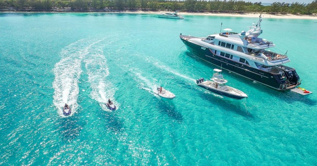 superyacht in the clear blue sea of the bahamas with tenders alongside 