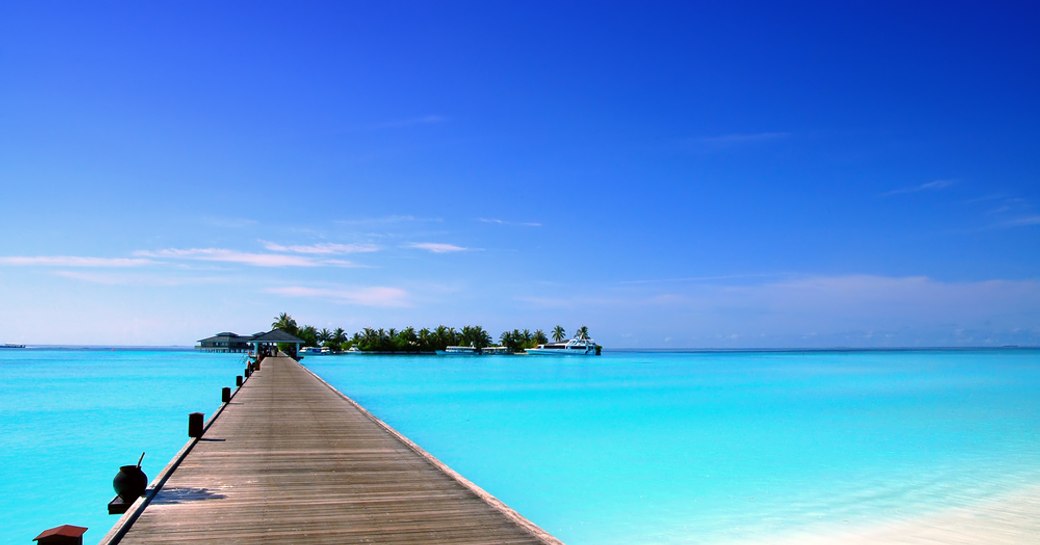 wooden pier stretching out over turquoise waters in the maldives