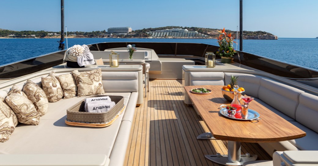 sun shining on motor yacht ANAMEL's aft deck with plush seating and al fresco dining table 