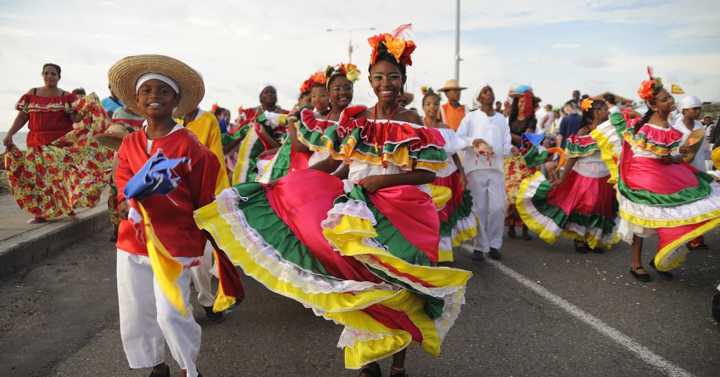 happy dancers in bright and colourful traditional dresses  parade down a road in a carnival on the us virgin islands