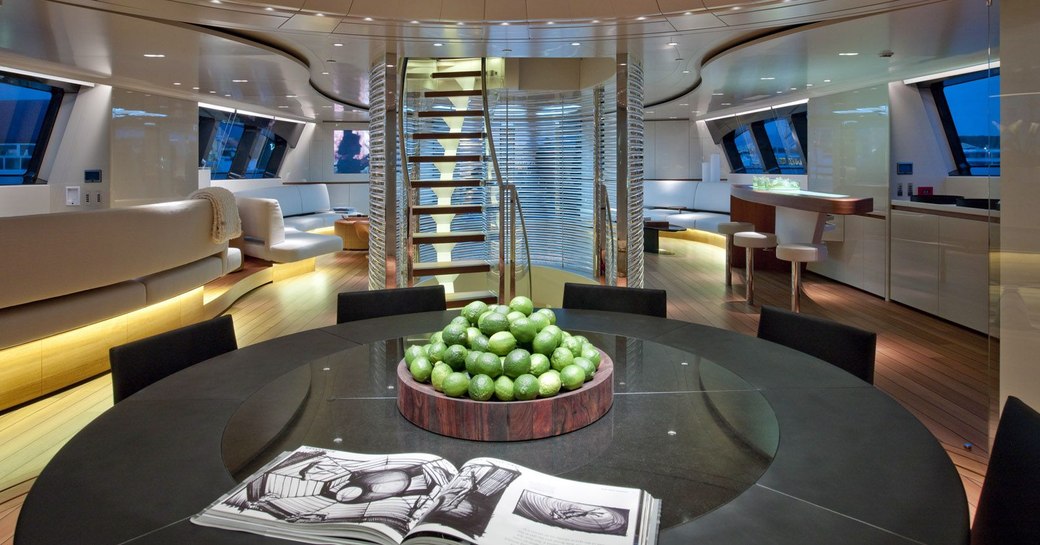 main salon on luxury sailing yacht panthalassa, with black table in foreground and staircase in background