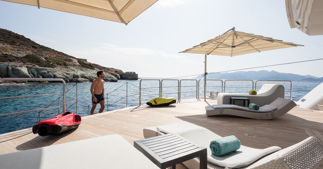 Man walking up to beach club on on superyacht O'PARI with sunloungers and teak decking