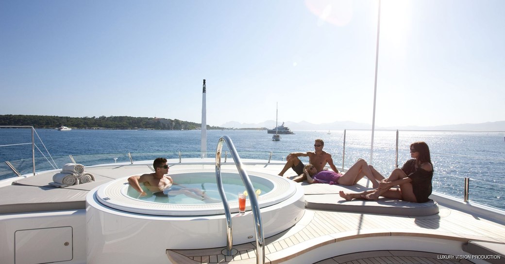 charter guests relax on sunpads next to jacuzzi on superyacht spirit 