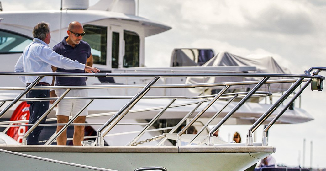 Two men in discussion on bow of motor yacht at Palm Beach International Boat Show.