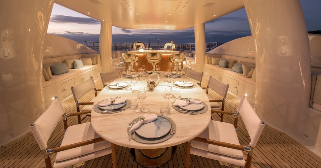 Superyacht DRIFTWOOD sun deck at night with dining table and jacuzzi beyond