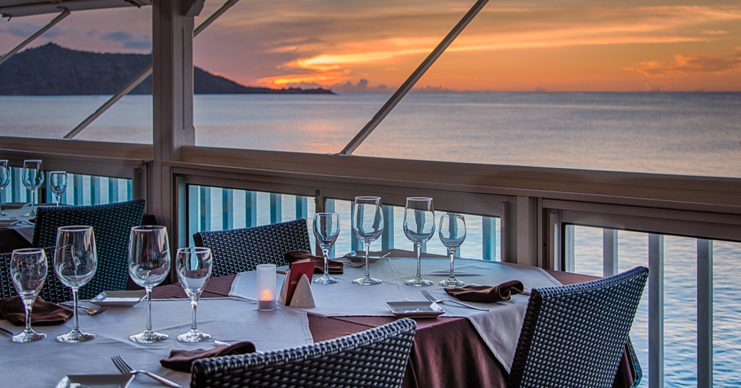 beach-side table is set for dining as the sun sets over the horizon in St Martin