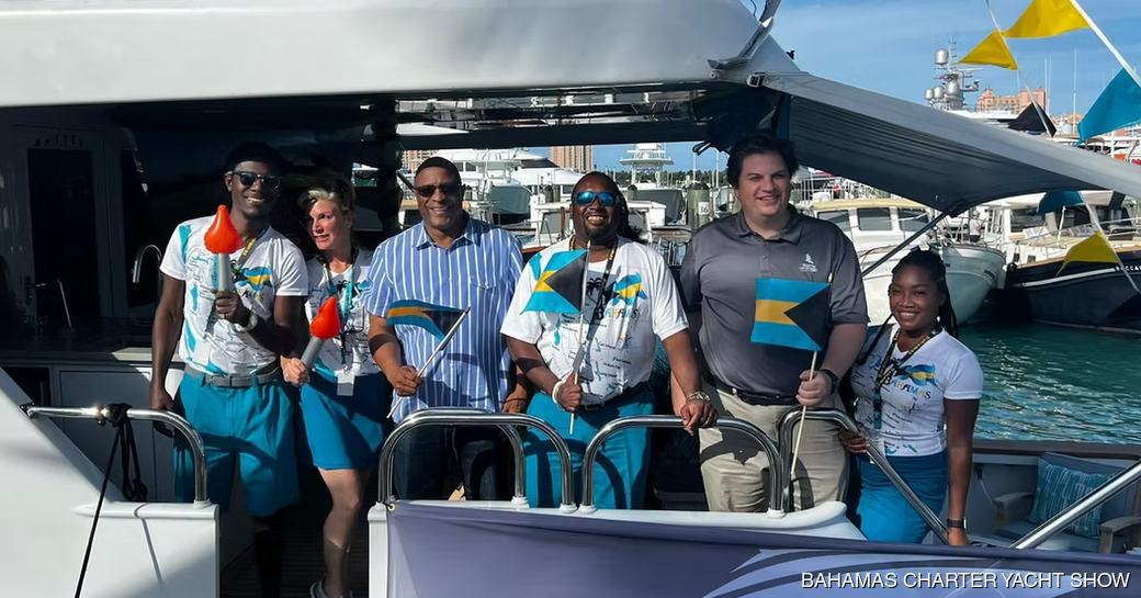 Bahamas Charter Yacht Show crew members with Bahamas flags on a yacht