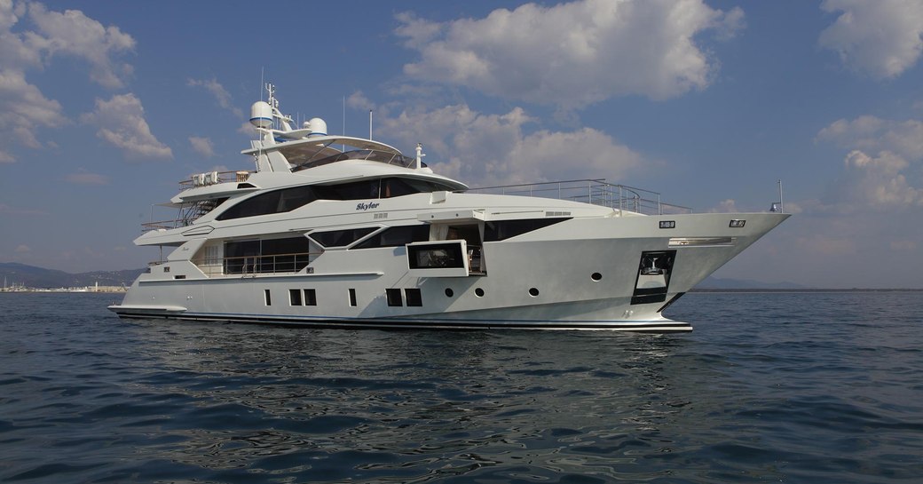 The bright white superyacht SKYLER cruising against a blue sky