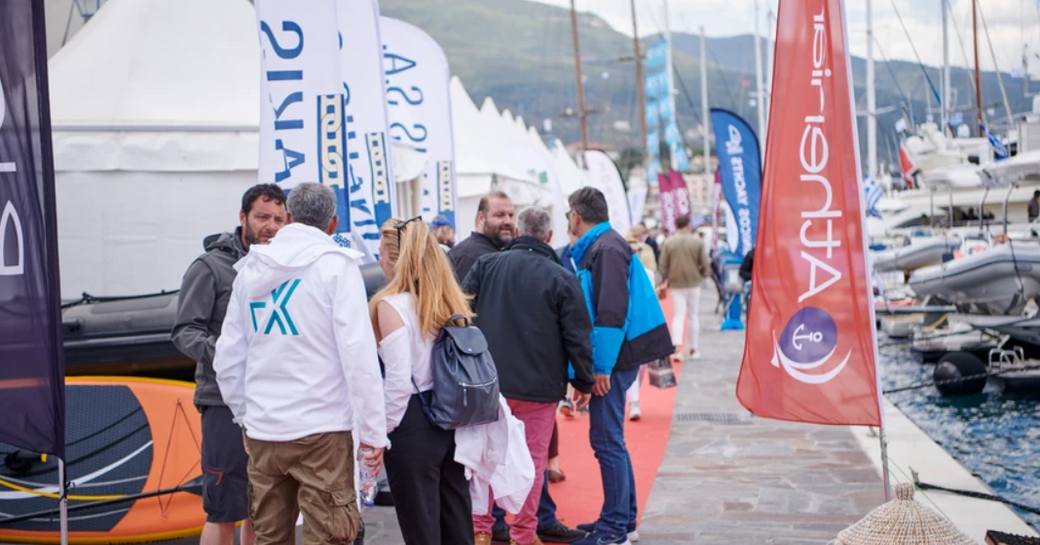 Visitors to the East Med Multihull & Yacht Charter Show standing on red carpet in discussion adjacent to displaying yacht charters