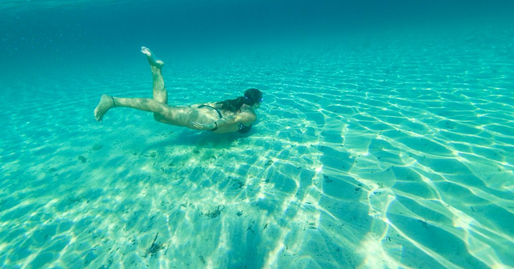 Woman on private yacht charter snorkels in clear blue sea in Ibiza