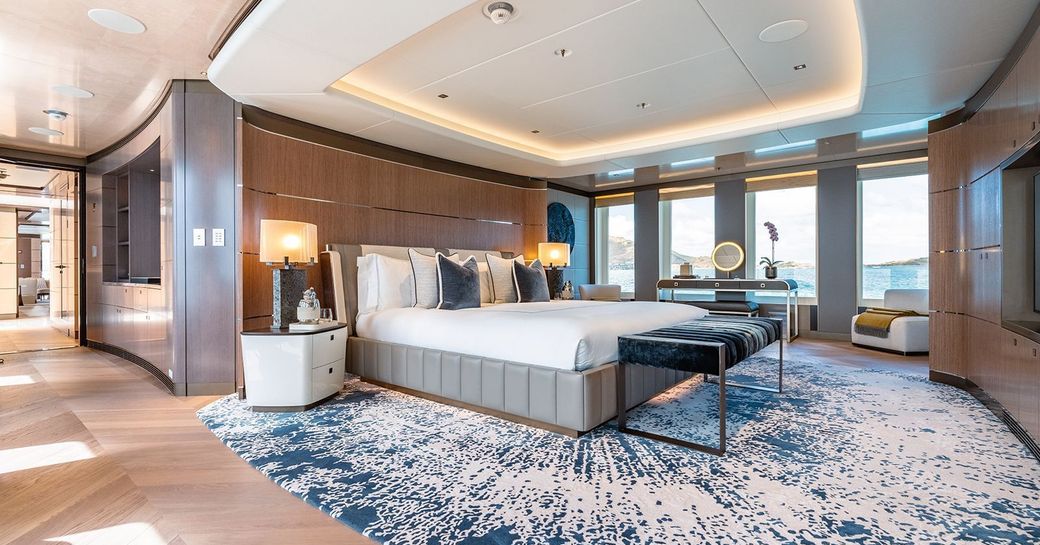 Master cabin onboard charter yacht MOSKITO, central berth with blue carpet underneath plus large windows aft 