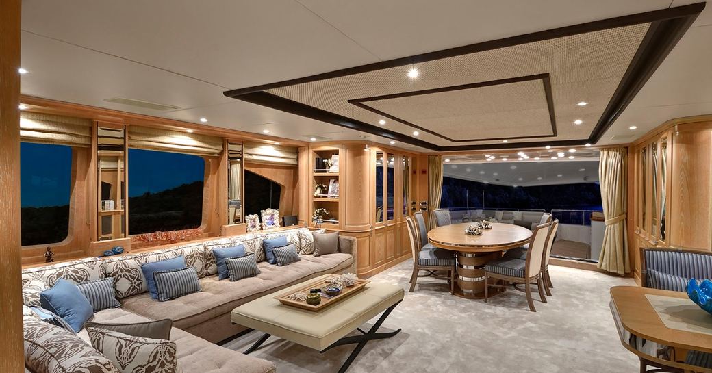 Main salon overview with plush lounge seating and aft dining area onboard charter yacht QUEST R