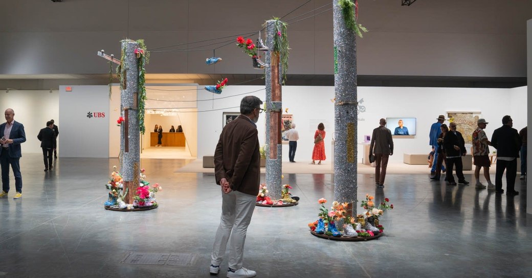 Male visitor viewing art sculptures in a gallery at Art Basel Miami.