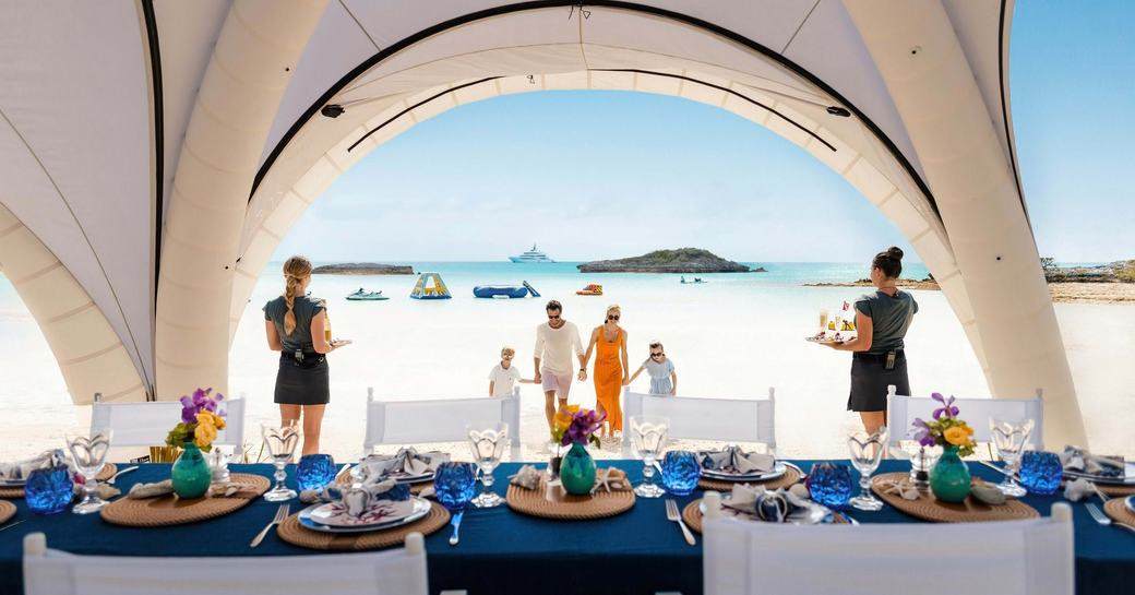 Stewardesses wait to serve guests at a beach barbeque ashore