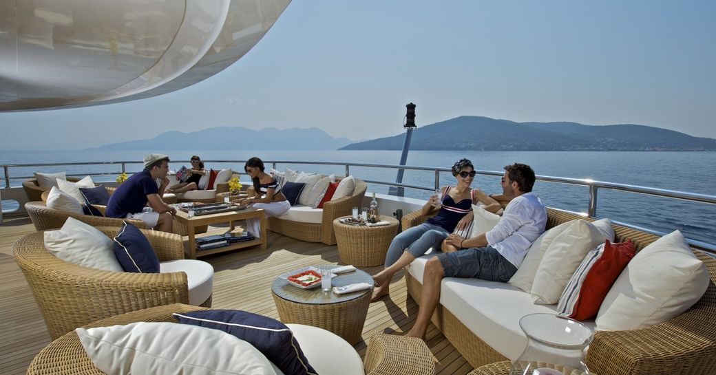 Guests on outdoor seating on deck of O'MEGA superyacht socialising