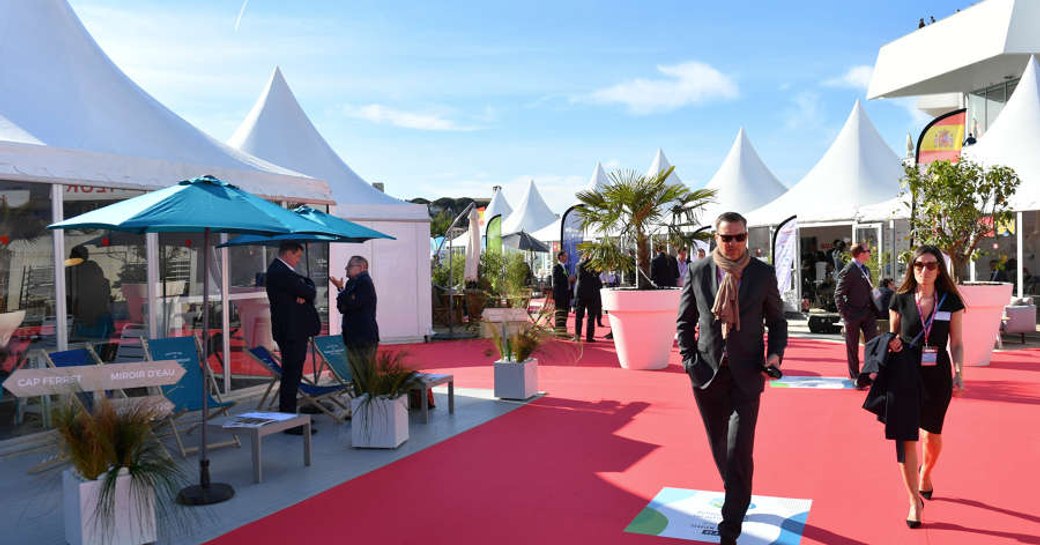 Exhibitors tents, red carpet and visitors walking round the Palais des Festivals during a MIPIM yacht charter.