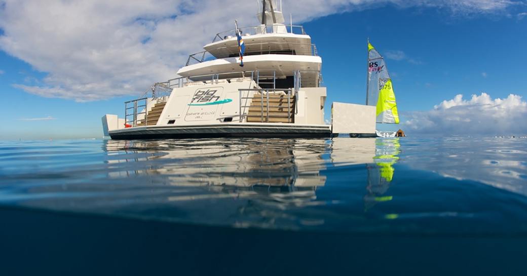 transom and stern of superyacht ‘Big Fish’ anchored next to wind surf