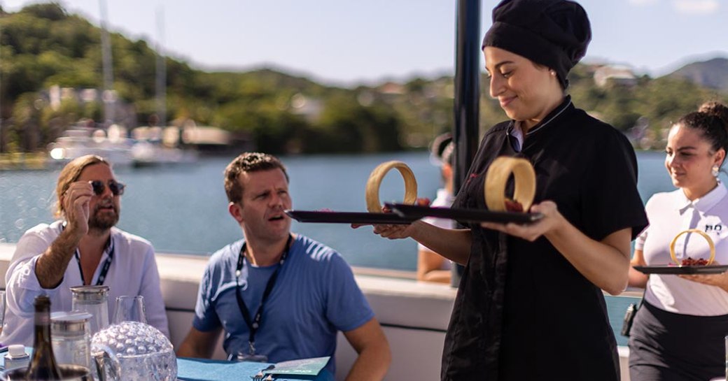 A superyacht chef serving plates during a chef competition