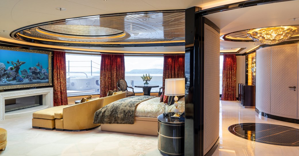 Master cabin onboard superyacht charter KISMET, with central forward-facing berth opposite a wall-mounted TV and large windows in the background