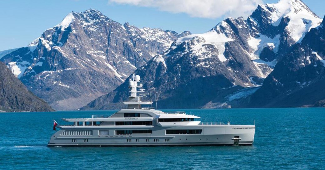 Expedition yacht CLOUDBREAK cruising against a mountainous backdrop