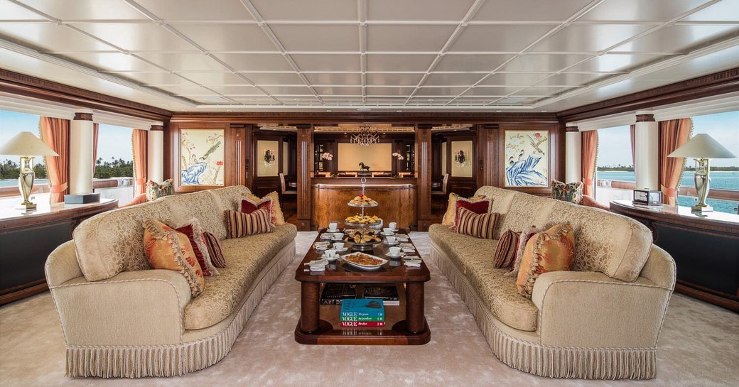 two sofas facing each other with cream tea setup on the coffee table in the main salon aboard luxury yacht CALYPSO