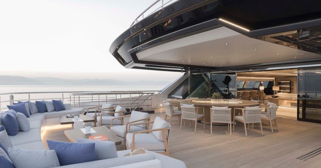 Overview of the aft deck onboard superyacht charter MALIA with large U-shaped sofa and freestanding chairs