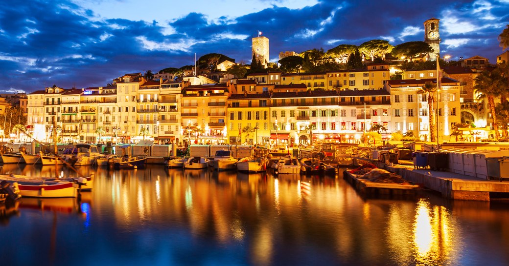 Overview of Cannes from the bay at dusk, all lit up against the night sky.