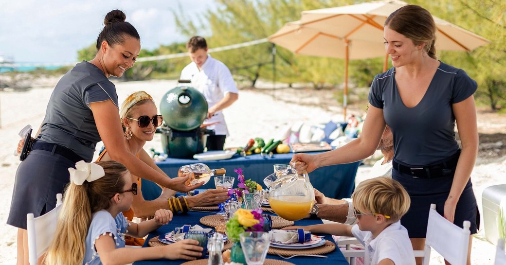 yacht crew serve food during beach picnic on charter vacation