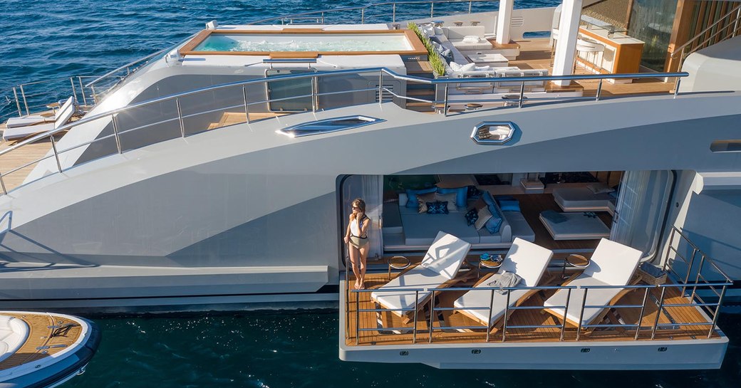 tatiana luxury yacht side balconies with furniture on the balcony and charter guest looking out to sea