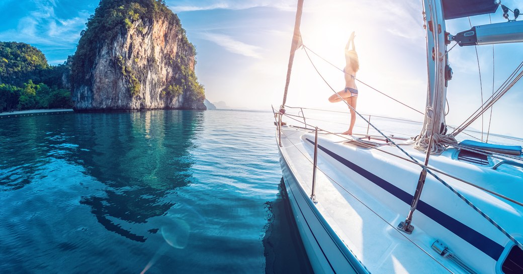 A woman performs a yoga pose on a sail yacht in Thailand