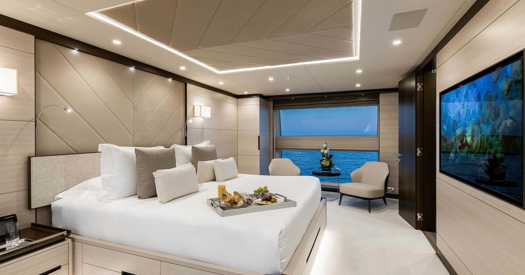 owners suite on board benetti yacht jacozami, with beautiful wide windows and large white bed