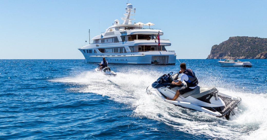 superyacht CALLISTO anchors in the Caribbean as charter guests play on the jet skis