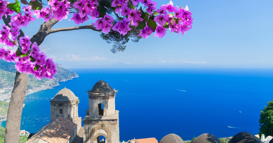 view of amalfi coast from the shore, ocean studded with superyachts for charter