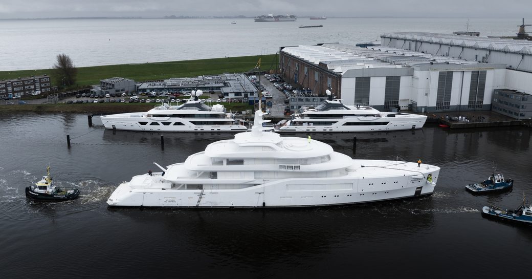  Amels 80 in transit with a pair of tug boats with other Amels superyachts berthed in the background