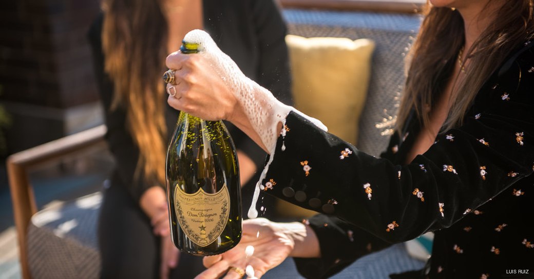 Charter guest on yacht opens bottle of Dom Perignon