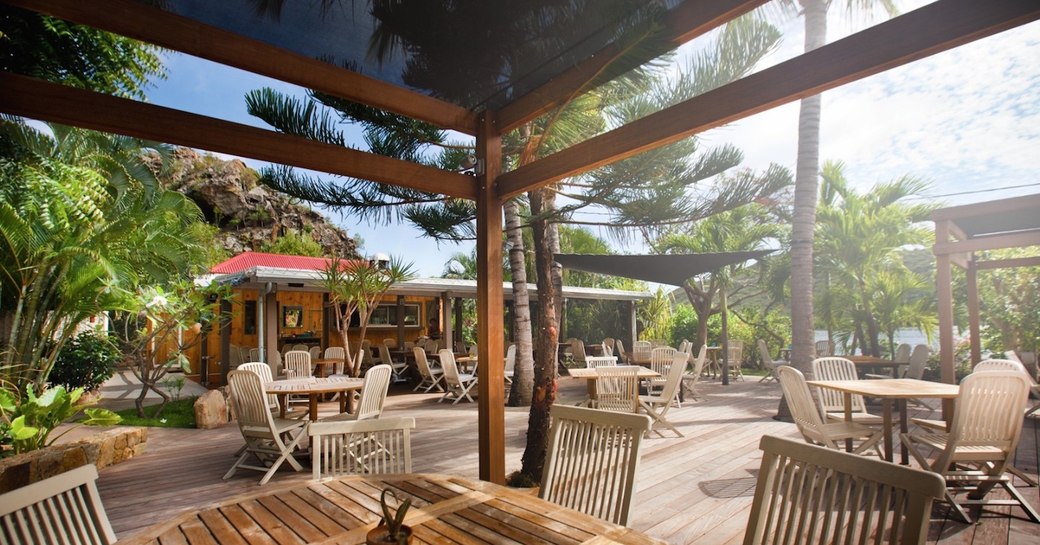 Outdoor tables and chairs interspersed with foliage  