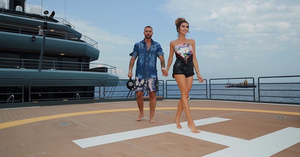 Designer Philipp Plein walking across helipad of explorer yacht RAGNAR with model