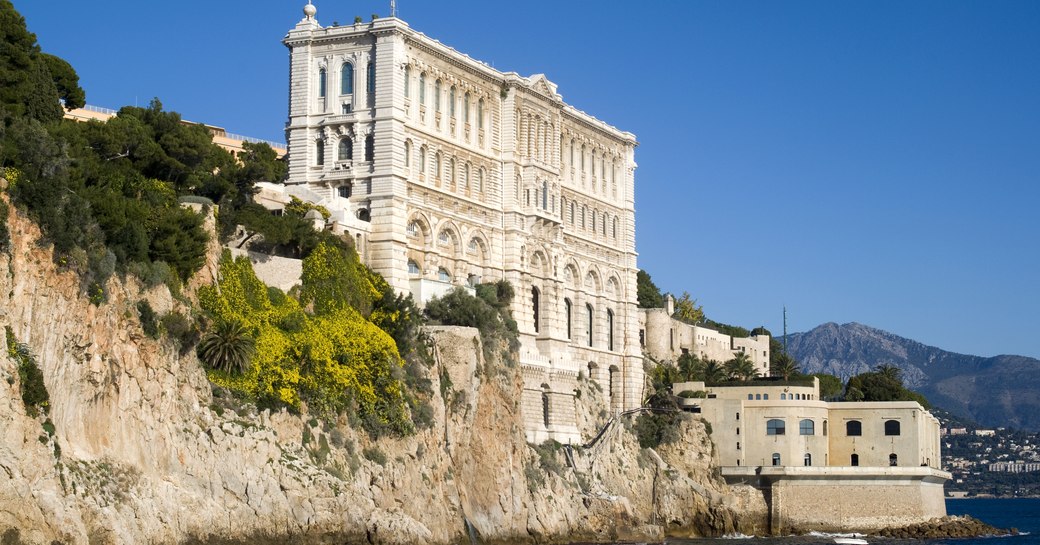 A sea-facing view of the Oceanographic Museum in Nice, a tall white building perched on the rock face