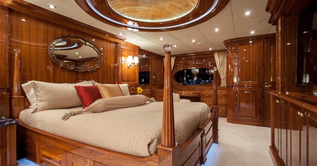 owners cabin on board luxury yacht, with polished wood and large bed in centre