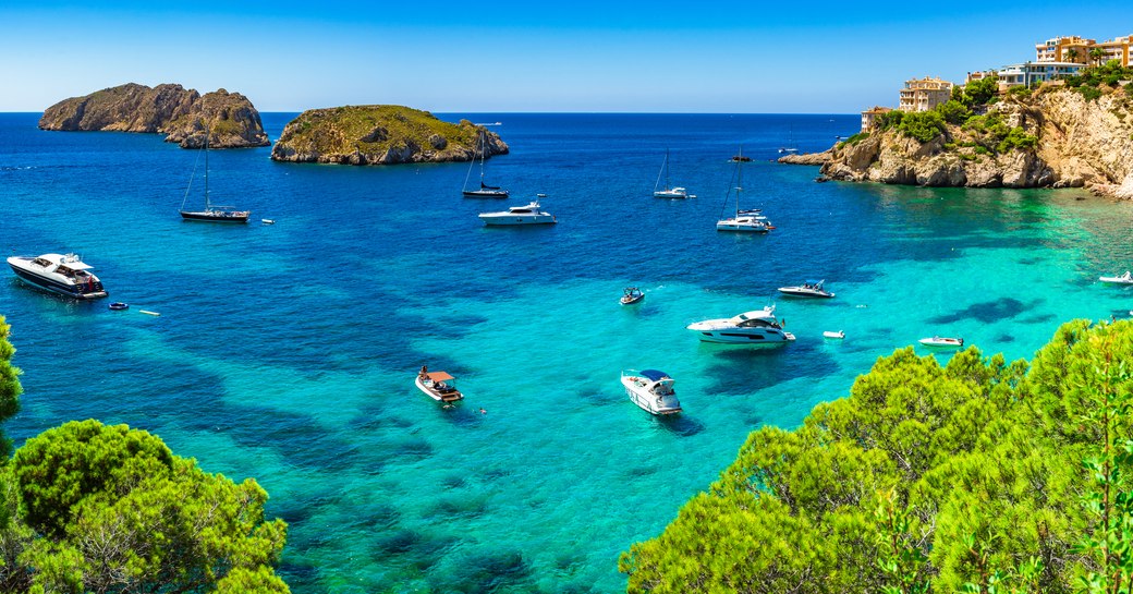 the beautiful and clear blue waters of a Mediterranean coast lined with superyacht 