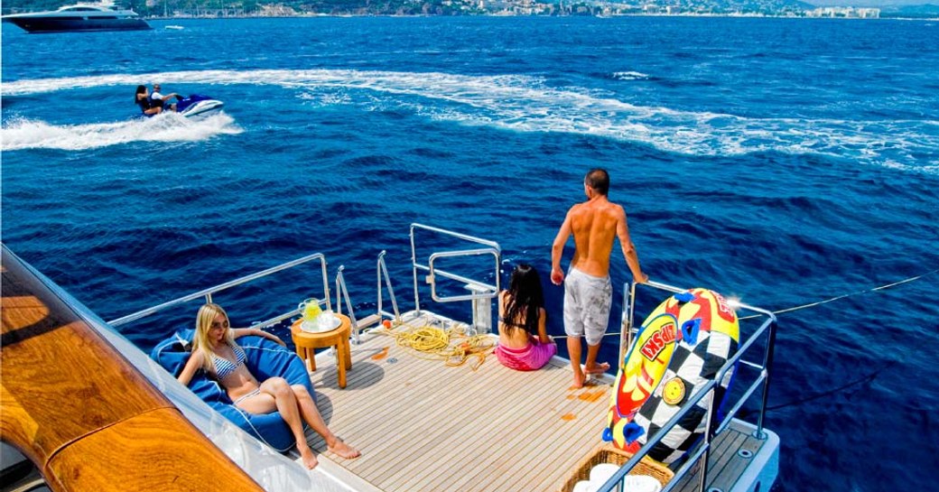 Couple on beach club of Illusion I yacht looking out at speedboat on sea