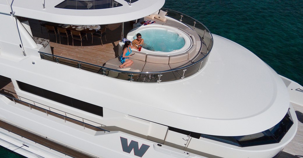 A charter guest sits in the Jacuzzi on the exterior of a superyacht with his girlfriend beside him