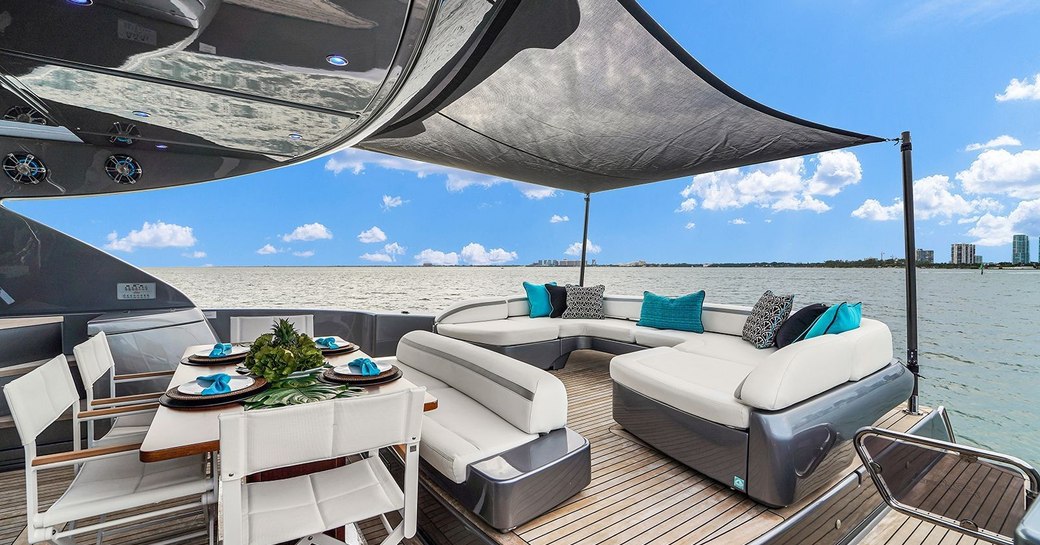 Overview of the aft deck onboard charter yacht GYPSEA, alfresco dining option and U-shaped seating with surrounding views of the sea.