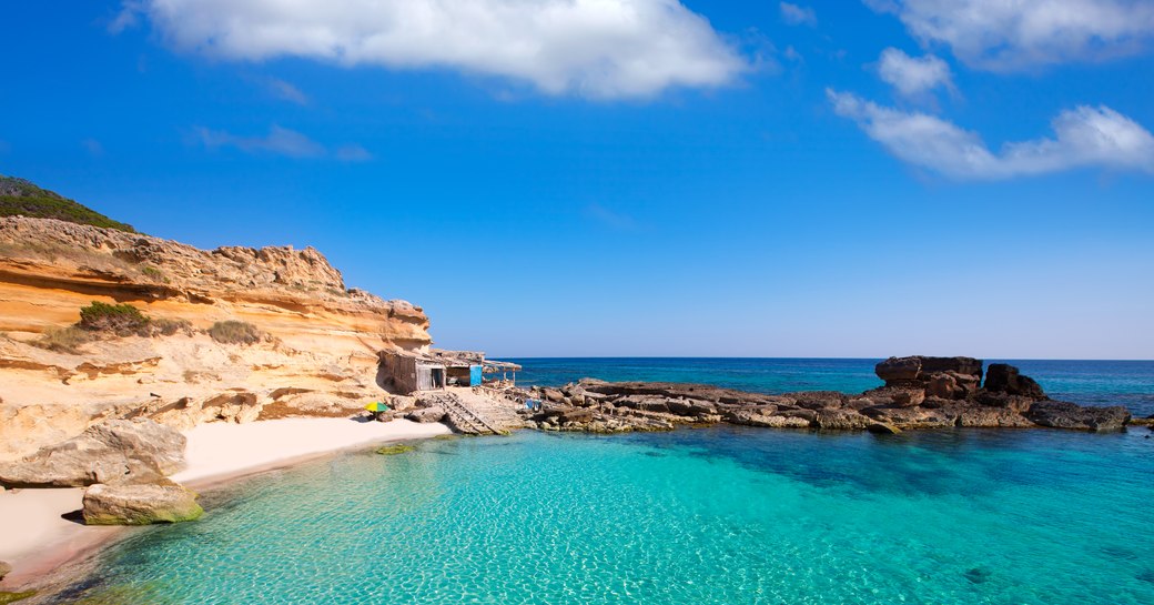 Sandy beach and clear blue sea in small bay on the island of Ibiza